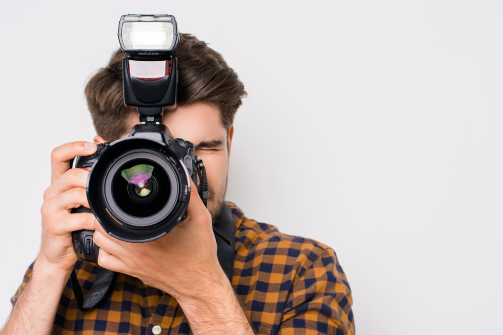 Young man focusing with digital camera  isolated on white background